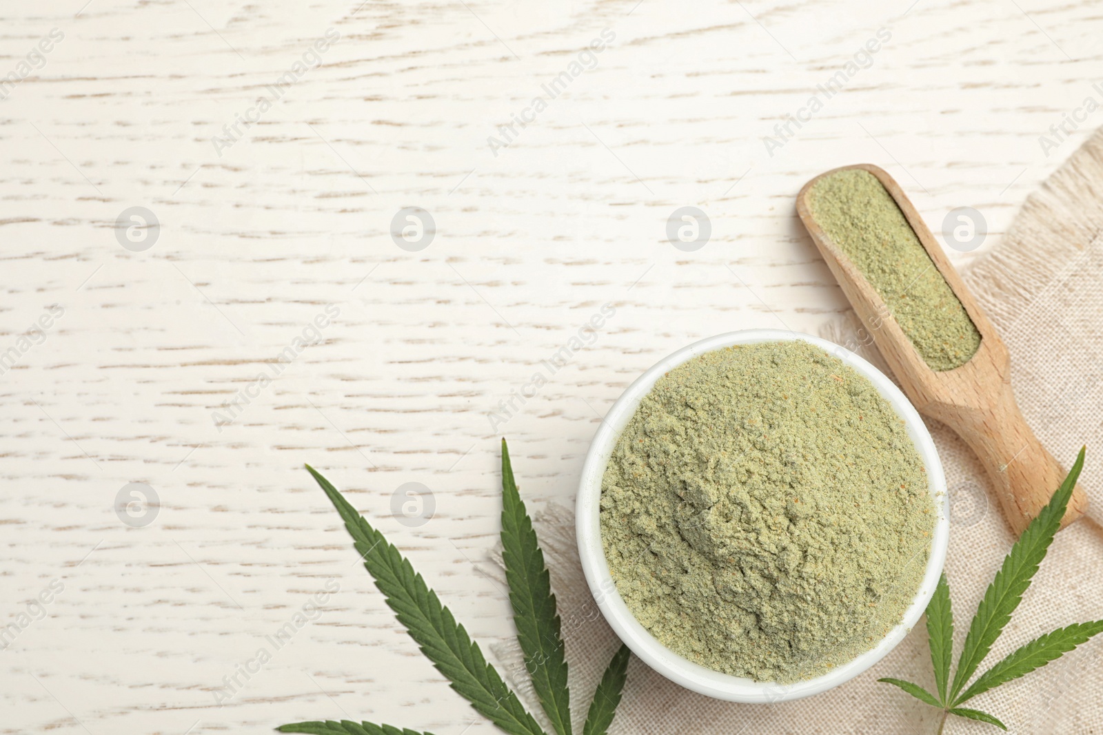 Photo of Flat lay composition with bowl of hemp protein powder on white wooden table. Space for text