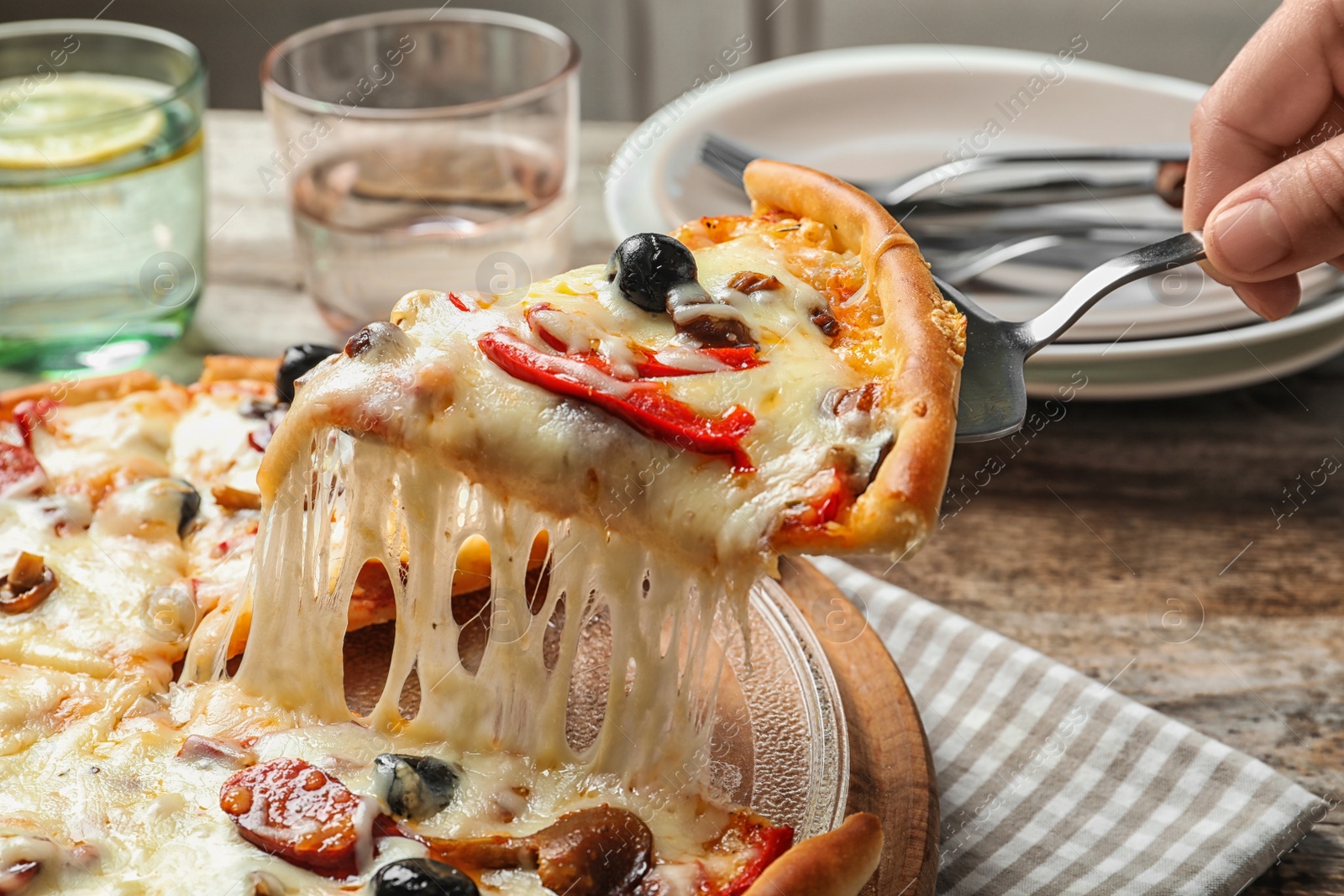 Photo of Woman holding shovel with slice of delicious hot pizza over table, closeup