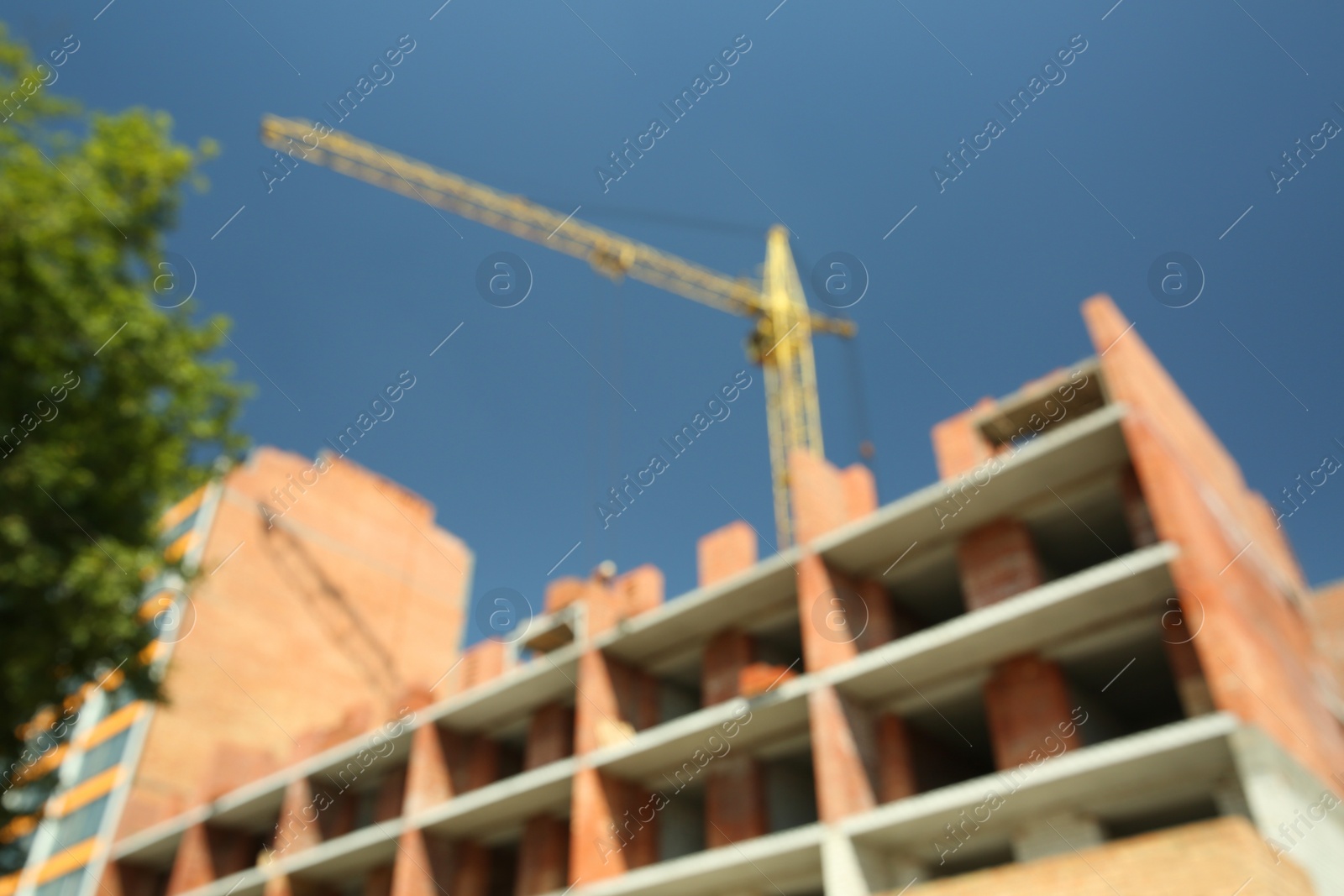 Photo of Blurred view of unfinished building and tower crane outdoors