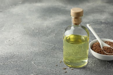 Photo of Bottle of essential oil and caraway (Persian cumin) seeds on light gray textured table