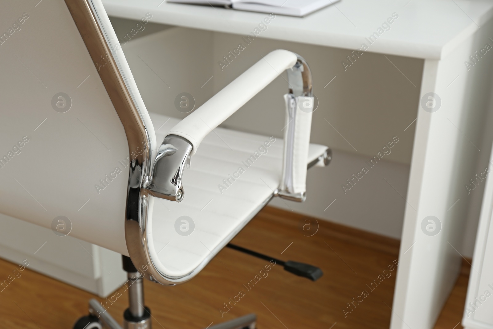 Photo of Modern office chair near table indoors, closeup. Stylish workplace interior