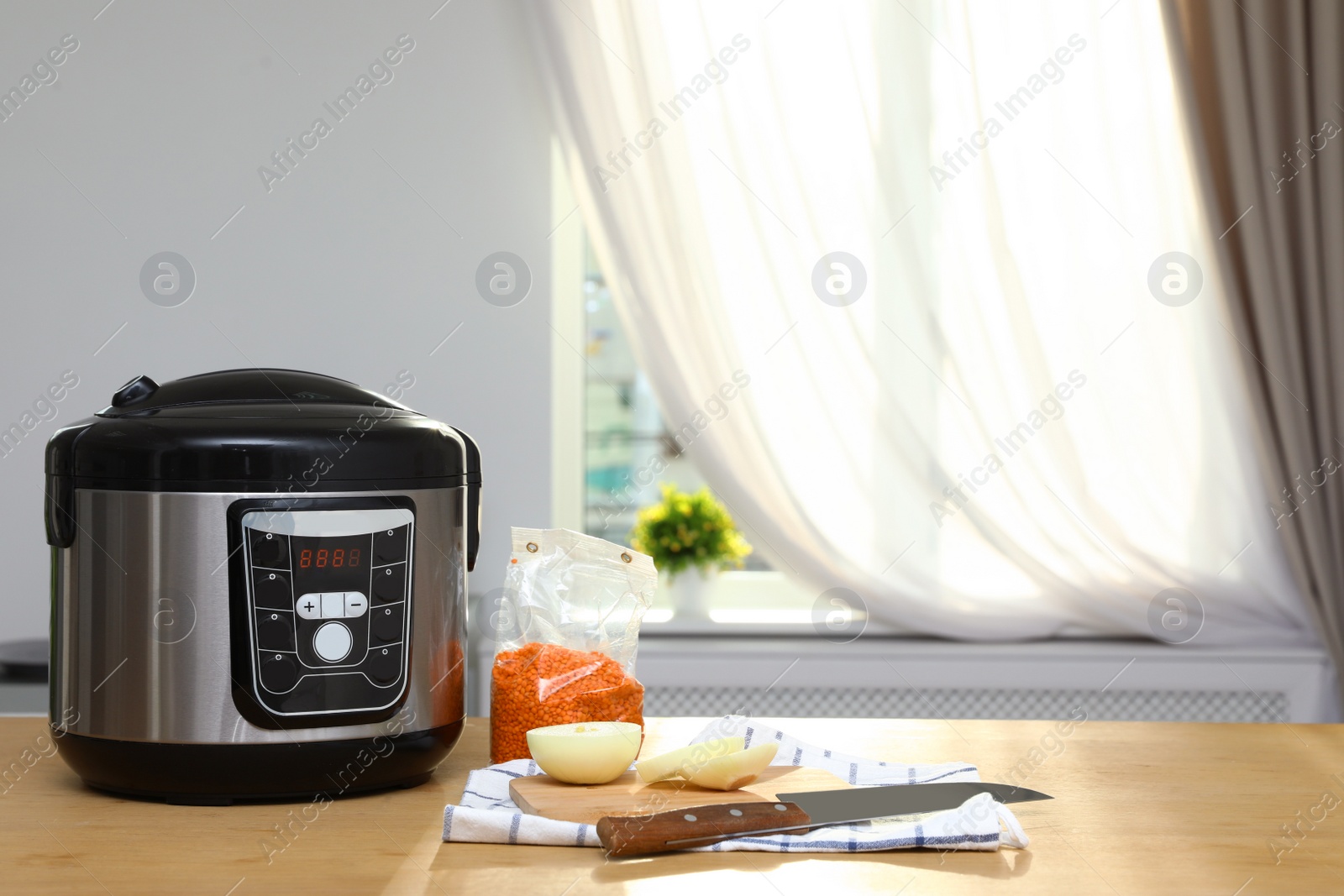 Photo of New modern multi cooker and products on table in kitchen. Space for text