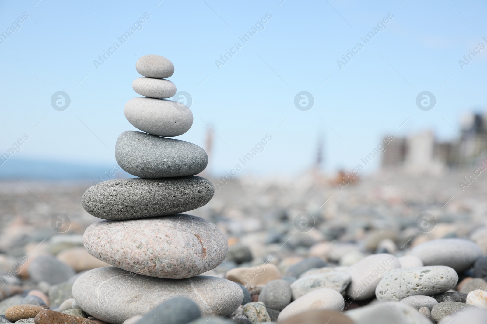 Photo of Stack of stones on beach against blurred background, closeup. Space for text