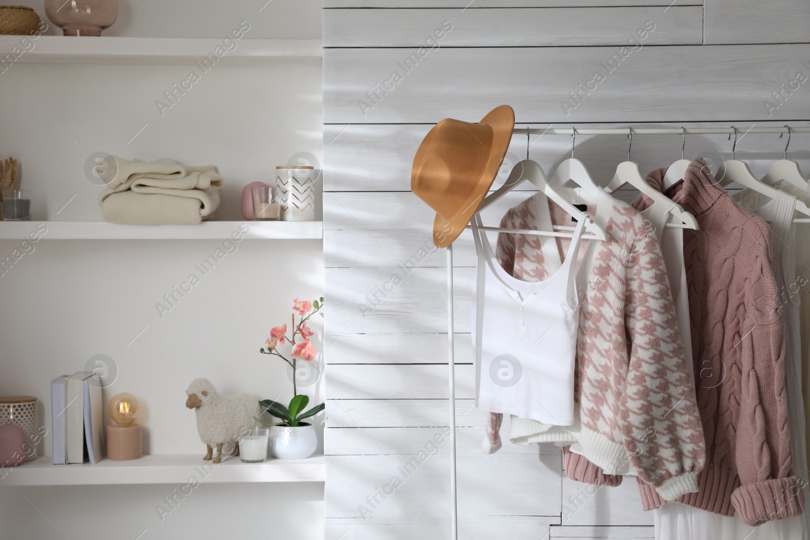 Photo of Rack with different stylish clothes, hat and decorative elements in dressing room