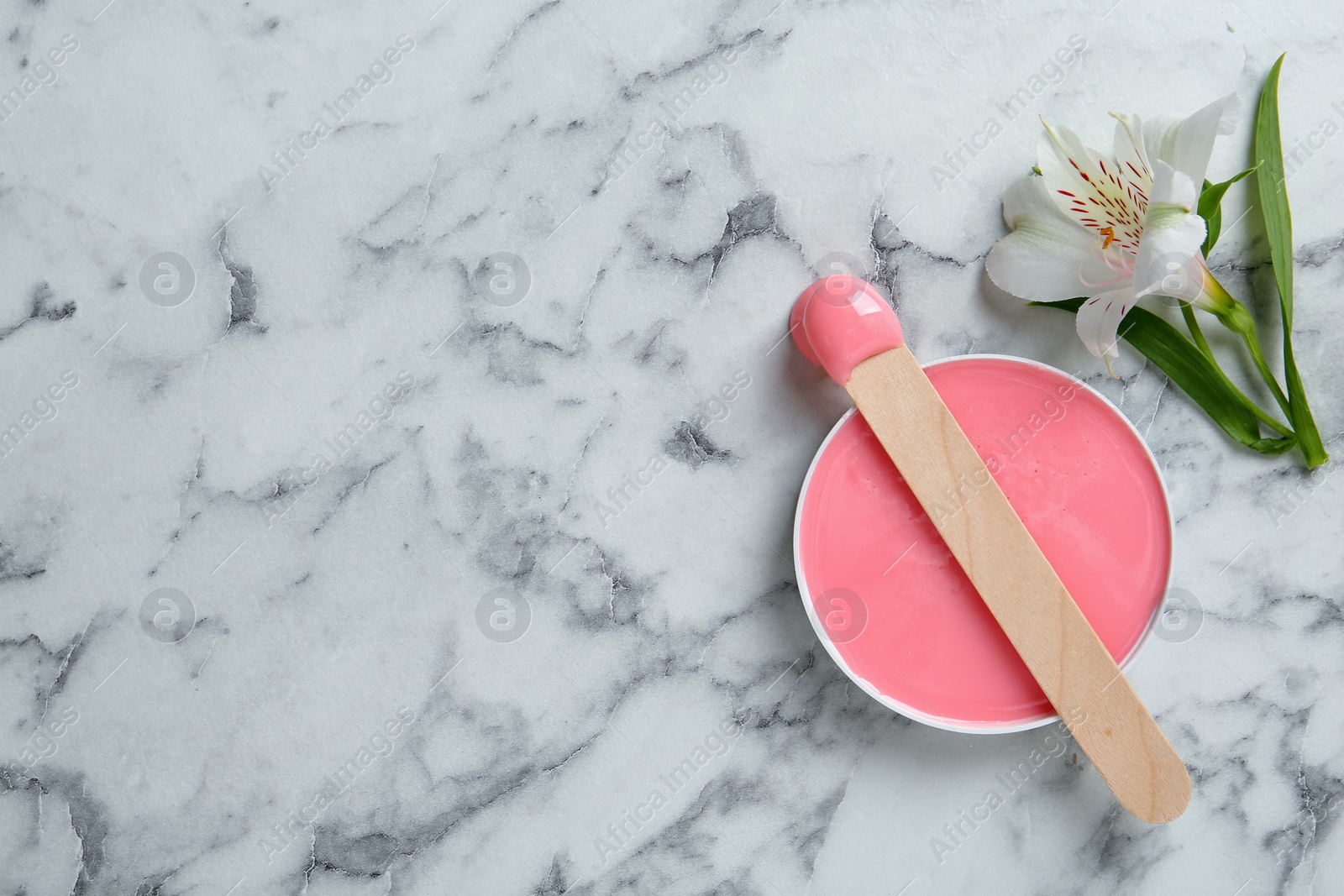 Photo of Spatula with wax and flower on white marble table, flat lay. Space for text