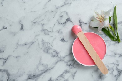 Photo of Spatula with wax and flower on white marble table, flat lay. Space for text