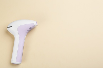 Photo of Modern photoepilator on beige background, top view. Space for text