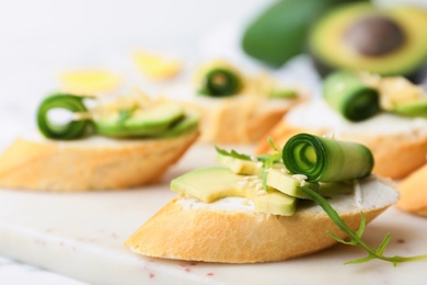 Photo of Delicious sandwiches with cucumber and avocado on white table