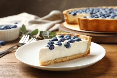 Photo of Plate with tasty blueberry cake on wooden table