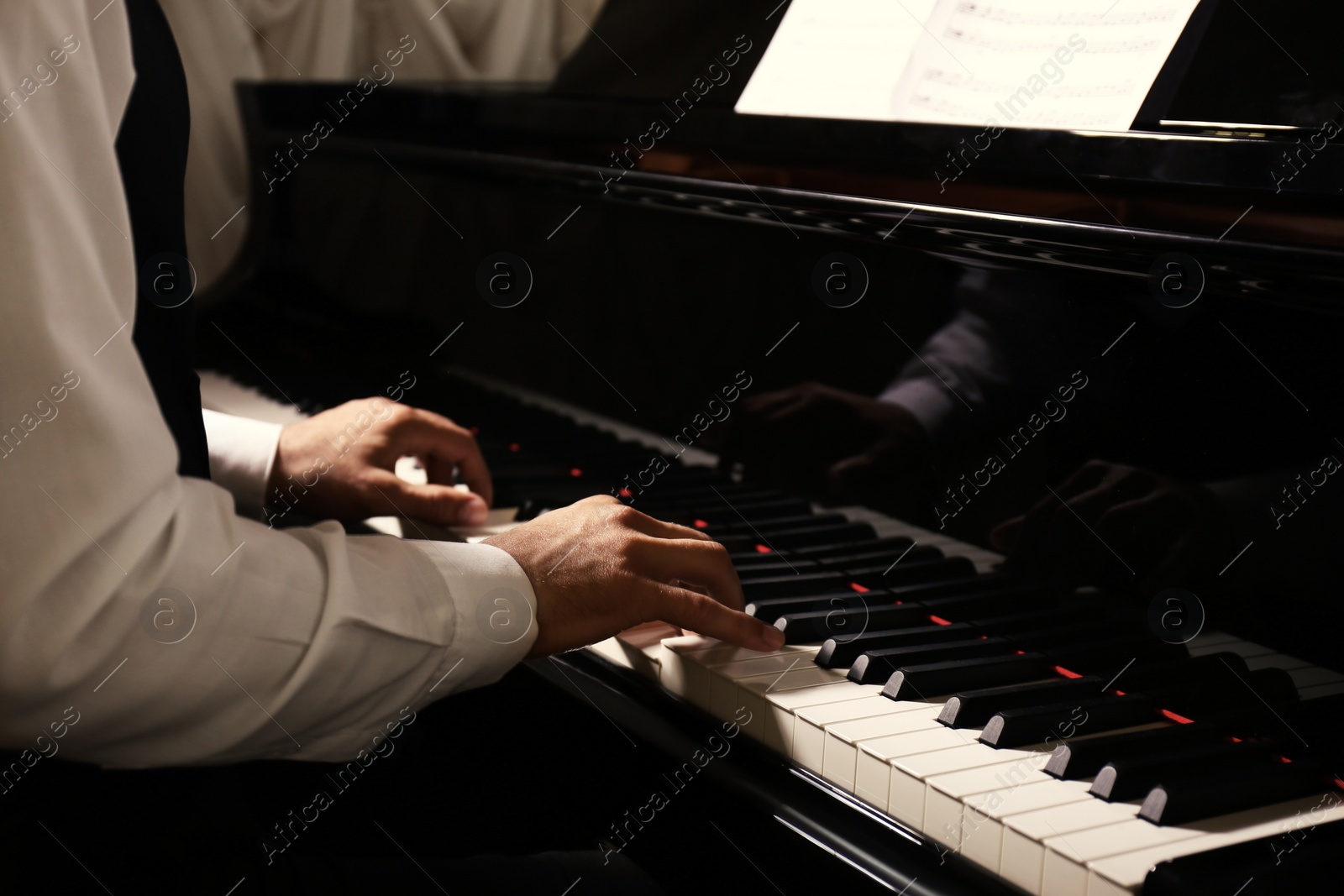 Photo of Man playing piano indoors, closeup. Talented musician