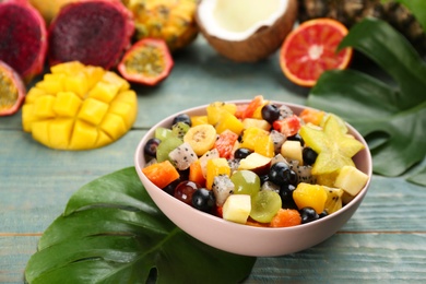 Delicious exotic fruit salad and ingredients on light blue wooden table