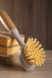 Photo of Cleaning brush and sponges on wooden table