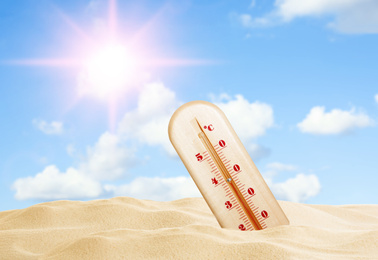 Weather thermometer with high temperature and sandy beach on sunny day