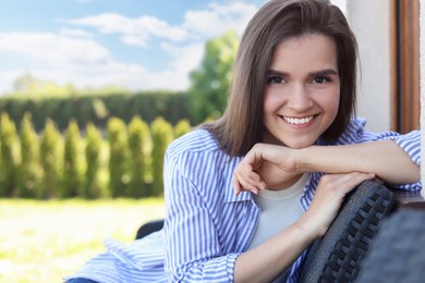 Photo of Portrait of beautiful young woman sitting on chair at backyard, space for text