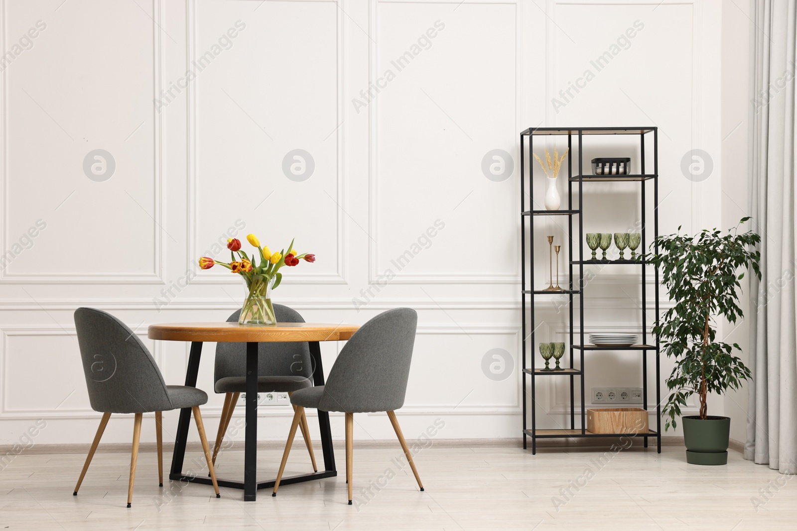 Photo of Stylish dining room interior with comfortable furniture and beautiful tulips