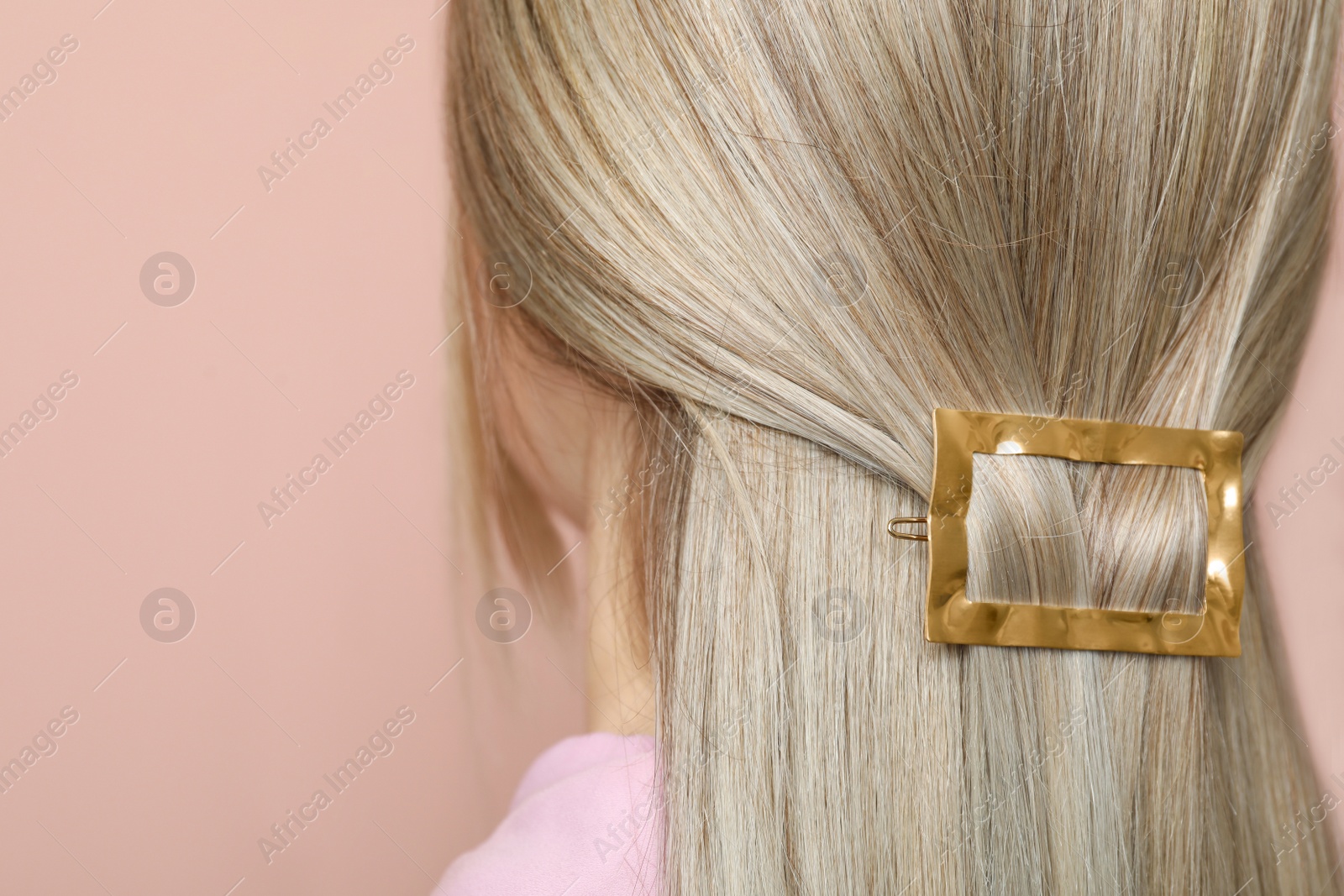 Photo of Young woman with beautiful gold hair clip on pink background, closeup