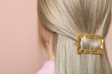 Photo of Young woman with beautiful gold hair clip on pink background, closeup