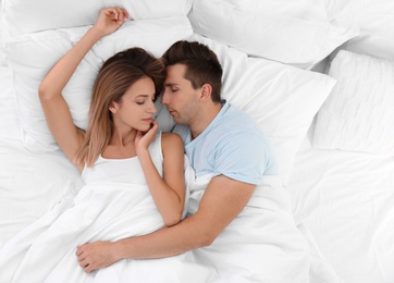 Photo of Young couple sleeping on soft pillows in bed at home