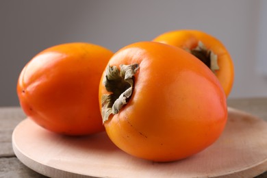 Photo of Delicious ripe persimmons on wooden table, closeup