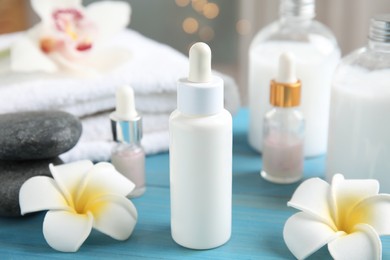 Photo of Beautiful spa composition with essential oil and plumeria flowers on turquoise table against blurred lights, closeup