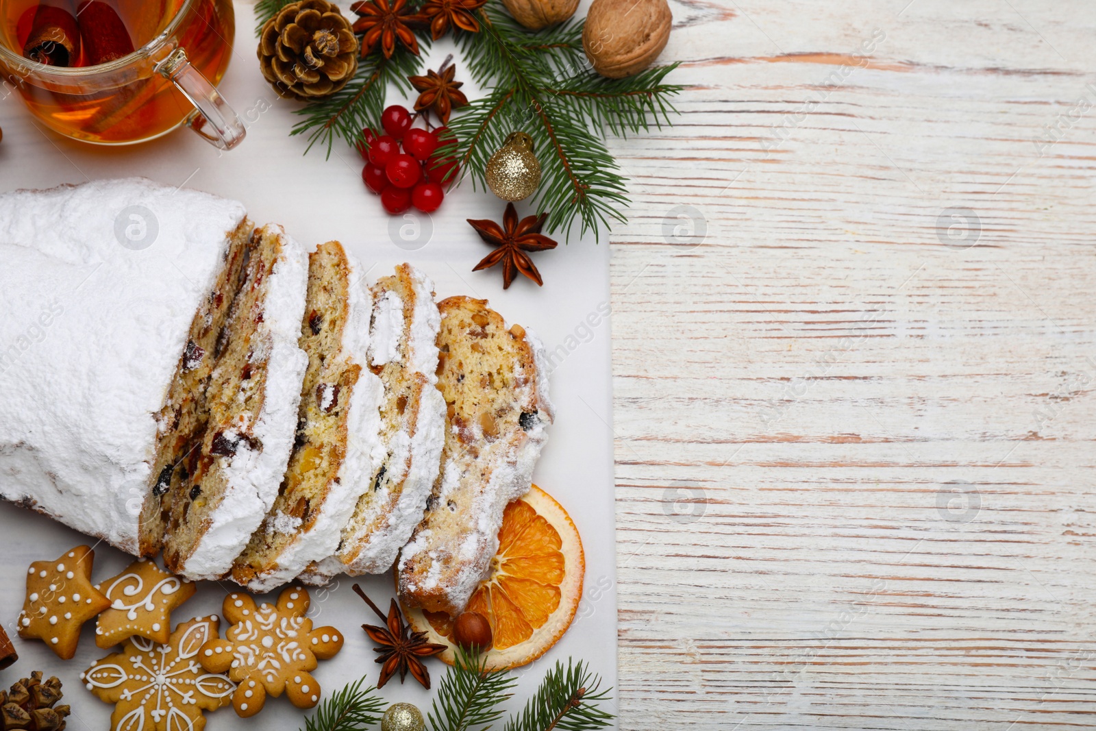 Photo of Traditional Christmas Stollen with icing sugar on white wooden table, flat lay. Space for text