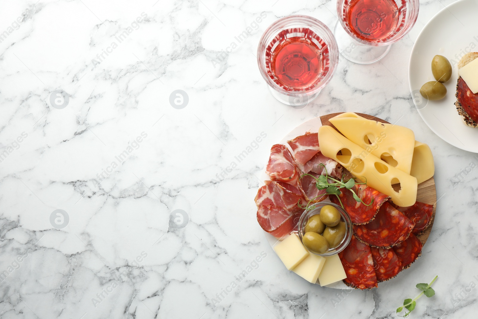 Photo of Serving board with delicious cured ham, cheese, sausage and olives on white marble table, flat lay. Space for text