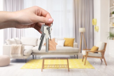 Woman holding house keys in room, closeup