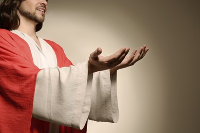 Photo of Jesus Christ reaching out his hands on beige background, closeup