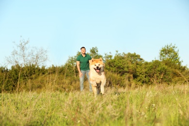 Photo of Young man with adorable Akita Inu dog in park