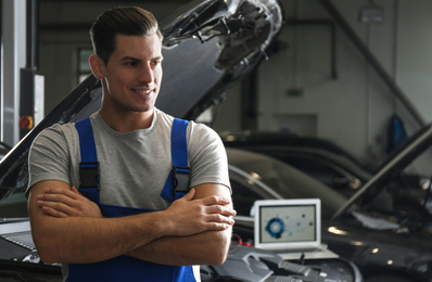 Mechanic near automobile in service center, space for text. Car diagnostic
