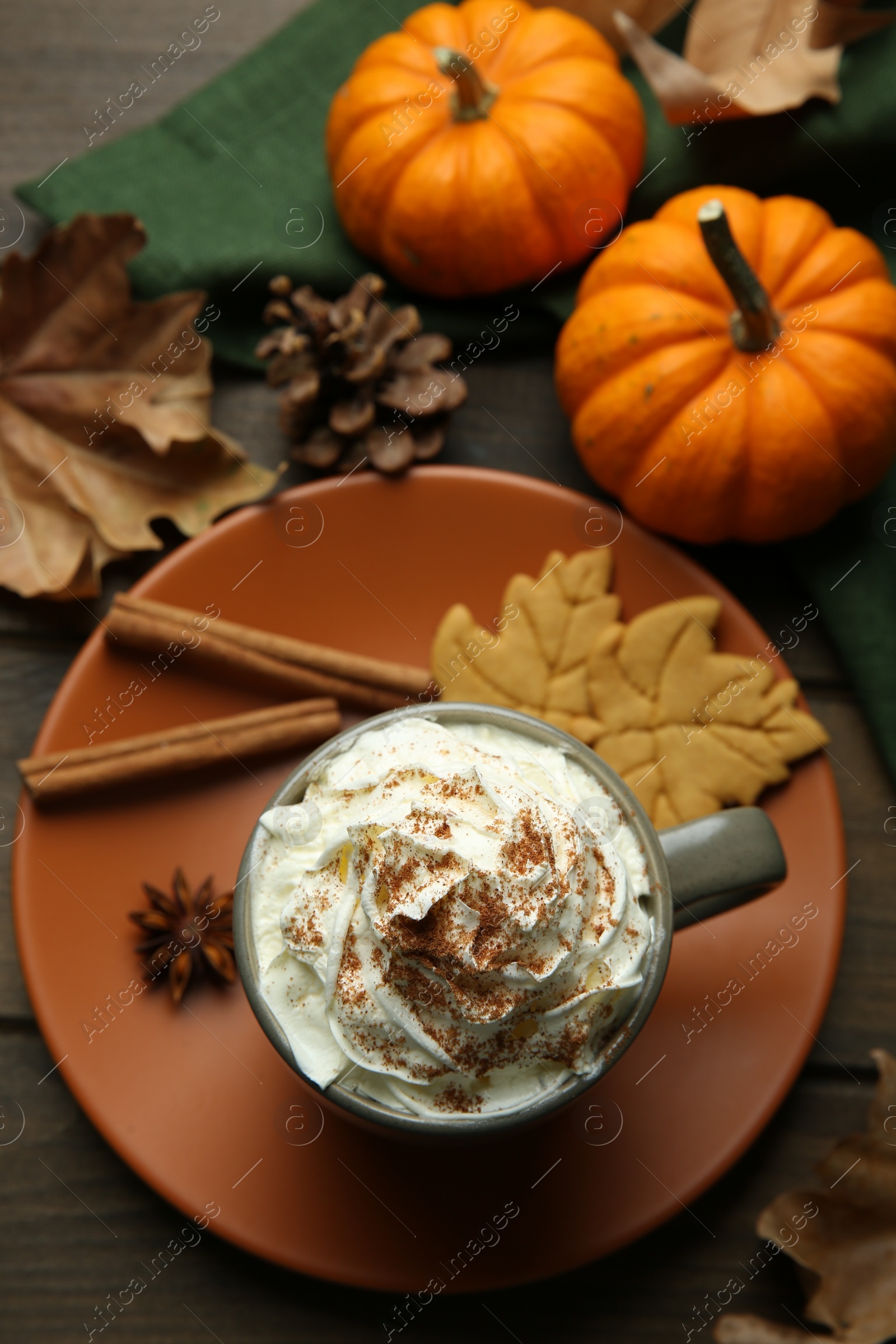 Photo of Flat lay composition of tasty pumpkin spice latte with whipped cream in cup on wooden table