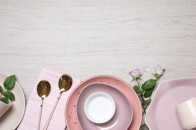 Photo of Flat lay composition with beautiful dishware and roses on white wooden table. Space for text