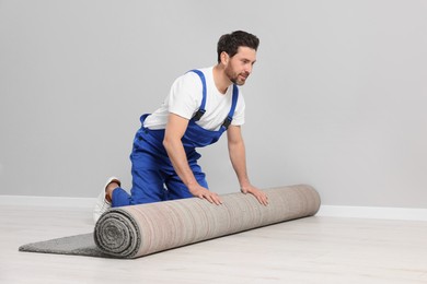 Worker unrolling new clean carpet in room