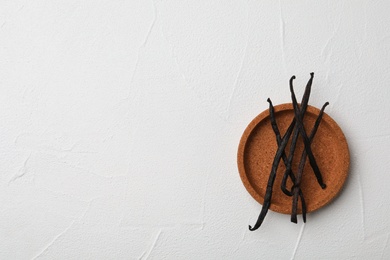 Plate with aromatic vanilla sticks on white background