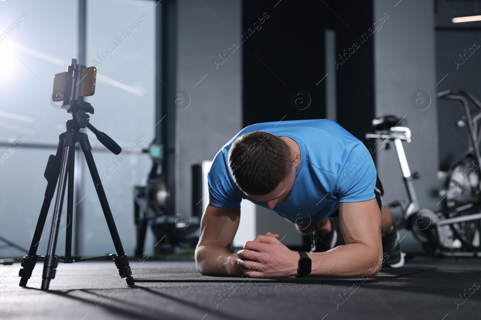 Photo of Trainer streaming online workout with phone at gym