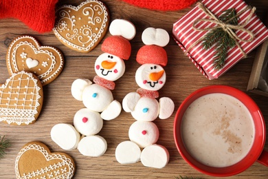 Photo of Flat lay composition with funny snowmen made of marshmallows on wooden table