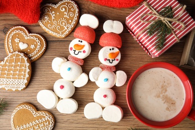 Flat lay composition with funny snowmen made of marshmallows on wooden table