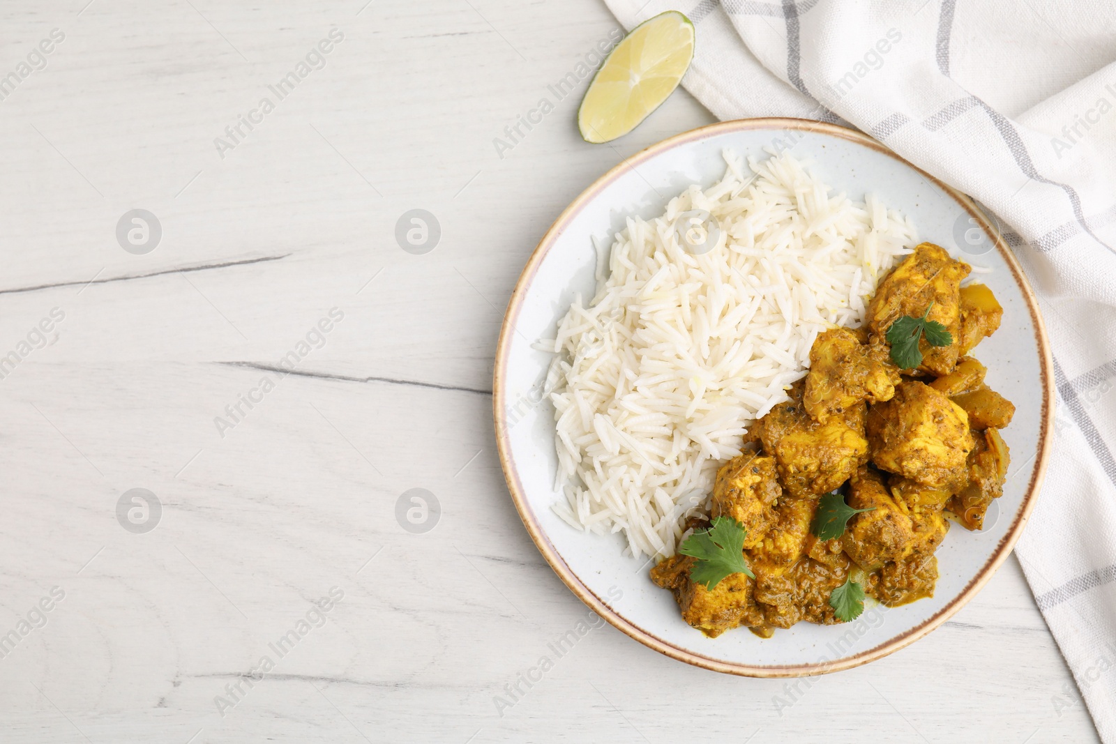 Photo of Delicious chicken curry with rice on white wooden table, top view. Space for text