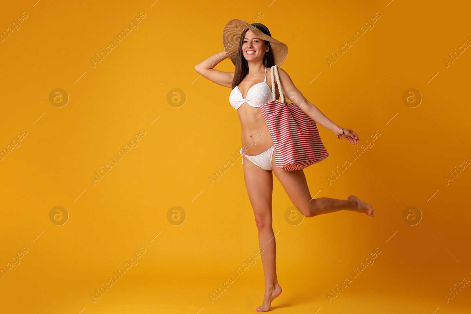 Photo of Pretty sexy woman with slim body in stylish  white bikini on orange background, space for text