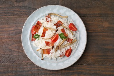 Photo of Delicious rice with bacon, mushrooms and tomatoes on wooden table, top view