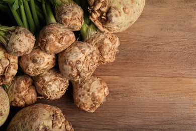 Photo of Fresh raw celery roots on wooden table, flat lay. Space for text