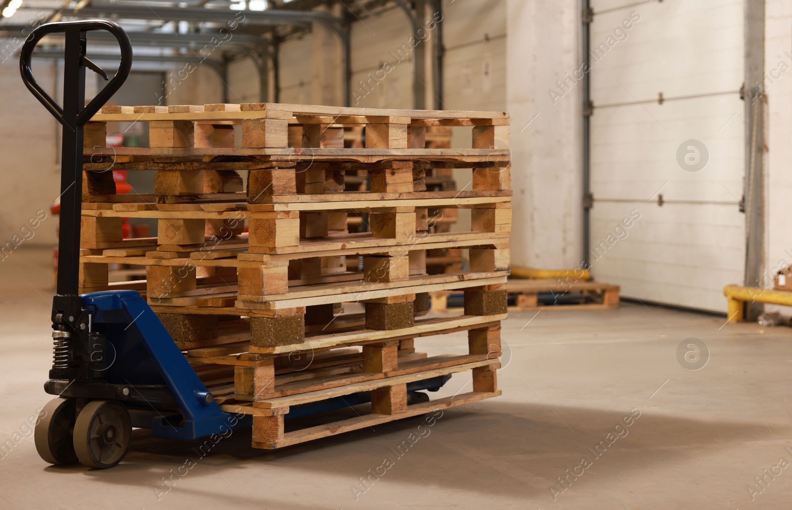 Image of Modern manual forklift with wooden pallets in warehouse, space for text