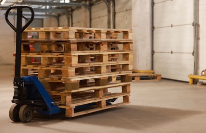 Image of Modern manual forklift with wooden pallets in warehouse, space for text