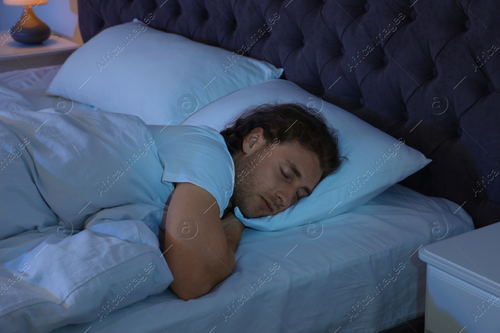 Photo of Handsome young man sleeping on pillow at night. Bedtime