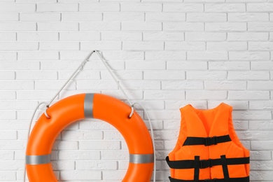 Photo of Orange life jacket and lifebuoy on white brick wall. Rescue equipment