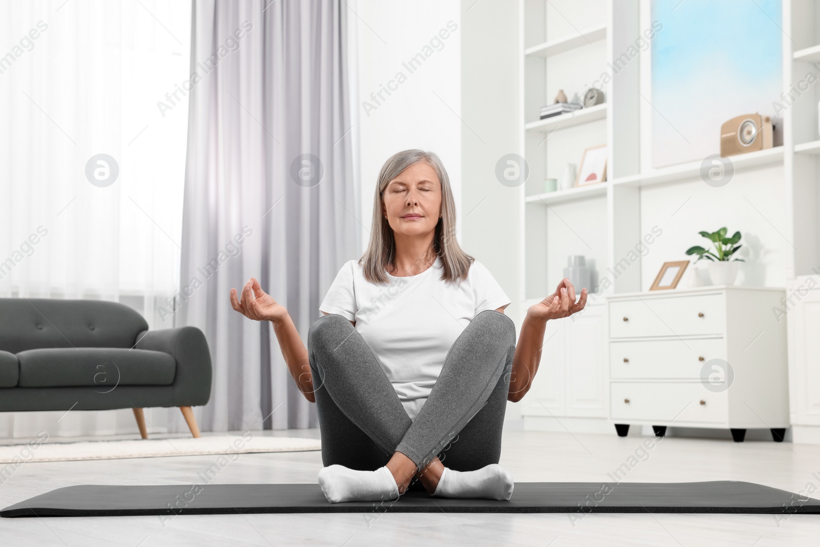 Photo of Senior woman practicing yoga on mat at home