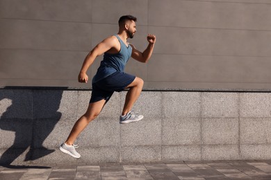 Photo of Young man running near building outdoors. Space for text