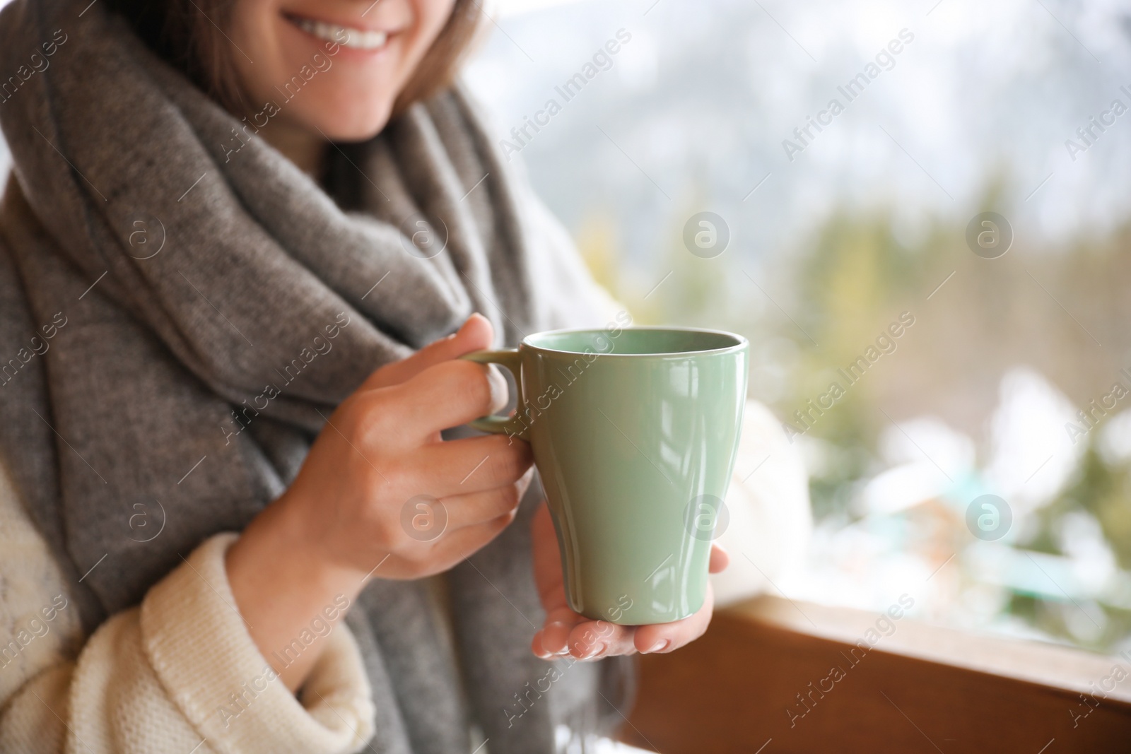 Photo of Woman with cup of tasty coffee outdoors on winter morning, closeup