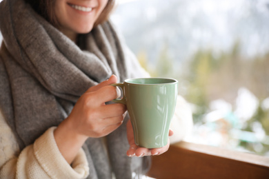 Photo of Woman with cup of tasty coffee outdoors on winter morning, closeup