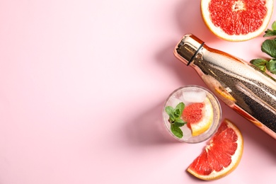 Photo of Flat lay composition with glass of infused water, grapefruits and bottle on color background. Space for text